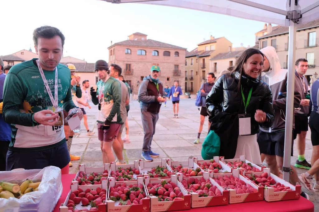 Corredores en el punto de avituallamiento de MUMU Berries tras cruzar la meta de la Media Maratón Cajaviva Segovia 2026